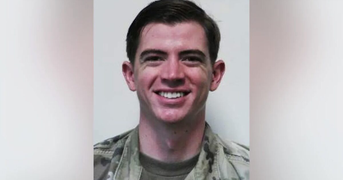 Smiling military personnel in uniform, posing against a neutral background, showcasing a friendly demeanor and professionalism.