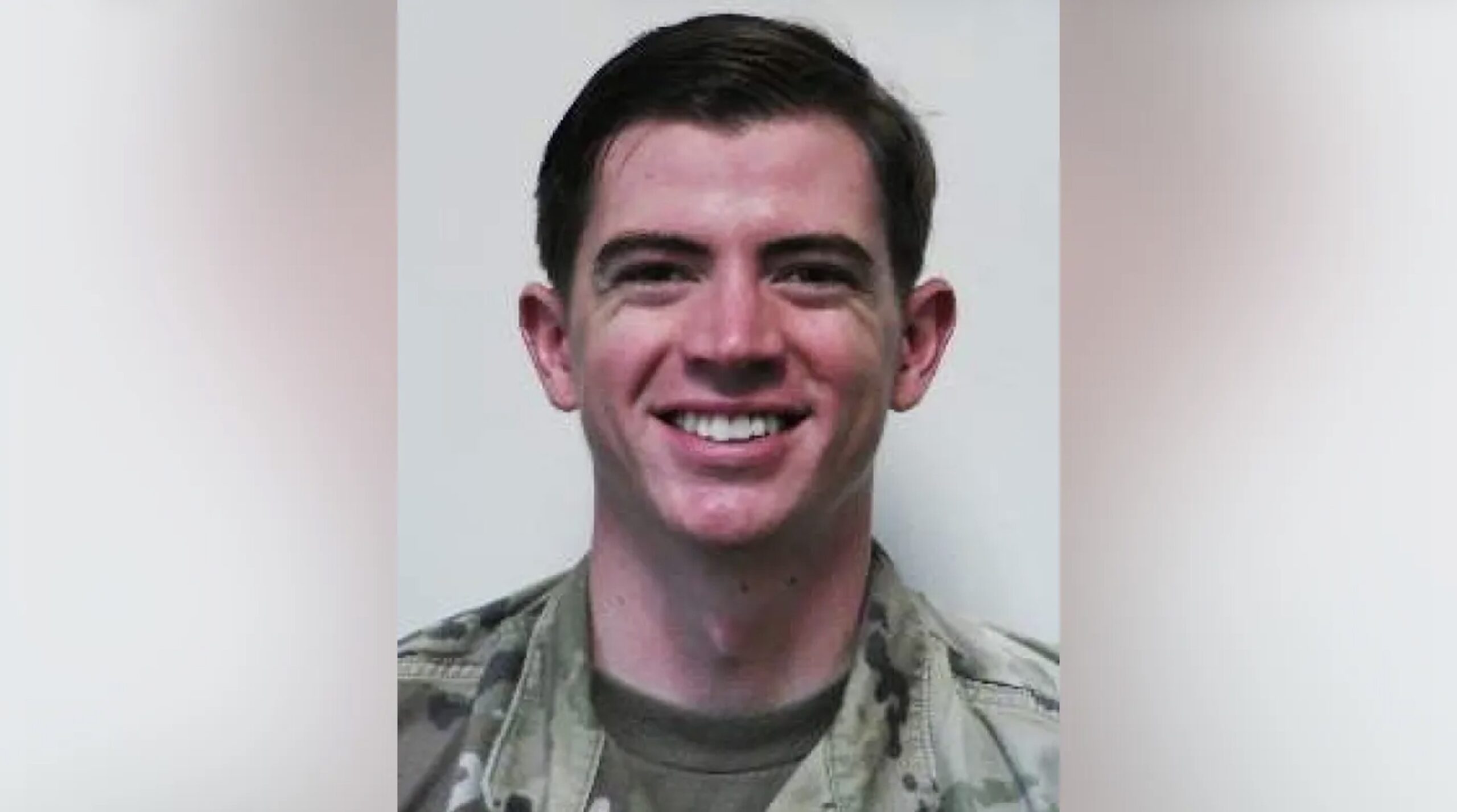 Smiling military personnel in uniform, posing against a neutral background, showcasing a friendly demeanor and professionalism.