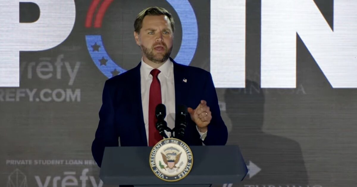 Speaker at a podium with the Vice President seal, addressing an audience during a political event, with a large backdrop displaying the word "POINT."