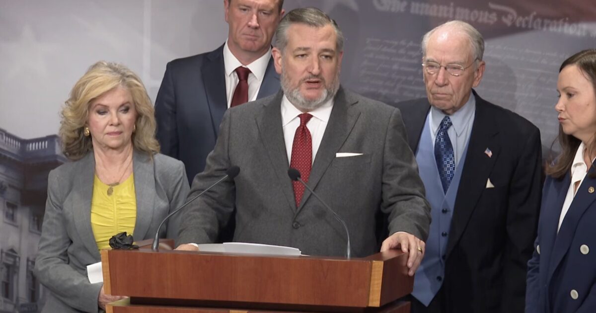 Ted Cruz speaks at a press conference with fellow lawmakers, addressing key legislative issues, with a backdrop featuring historical documents.