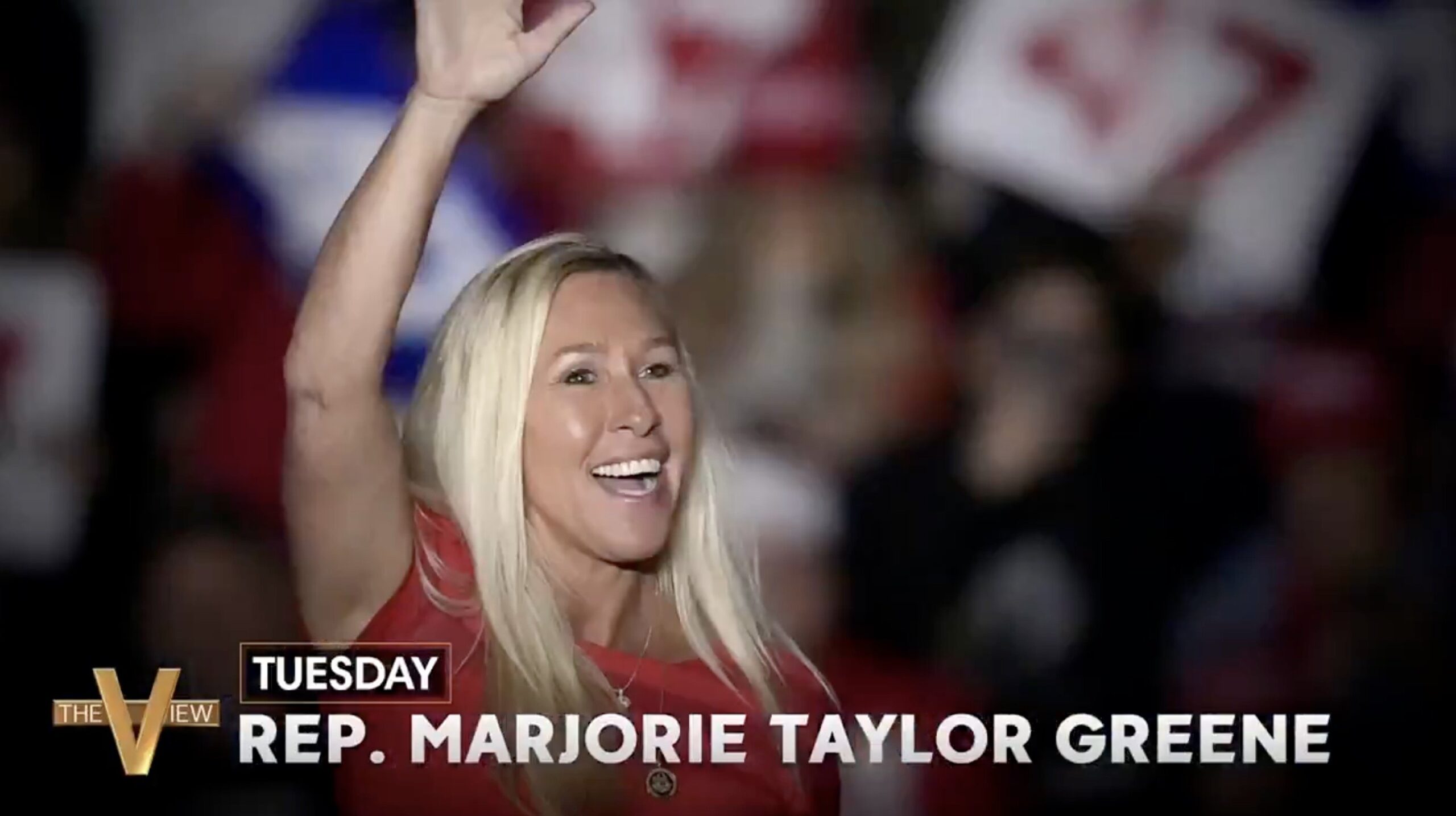 Rep. Marjorie Taylor Greene smiles and waves to a crowd during a political event, showcasing her engagement with supporters.