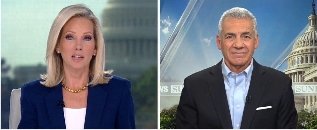 News anchors discussing current events with the U.S. Capitol in the background, showcasing a professional broadcast setting.