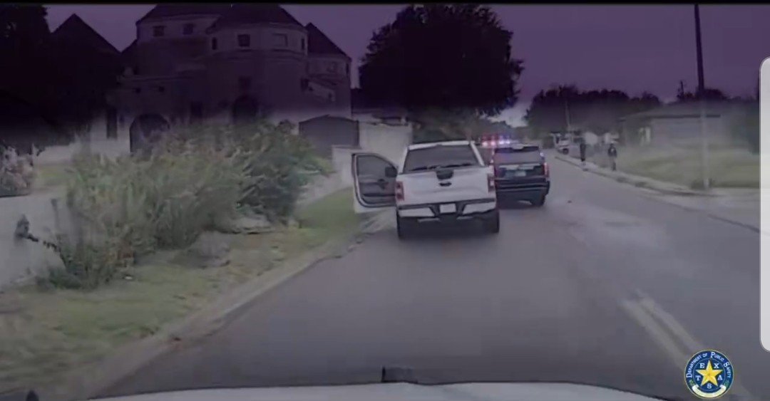 Police vehicles respond to a situation on a residential street, with one truck parked and another approaching with flashing lights.