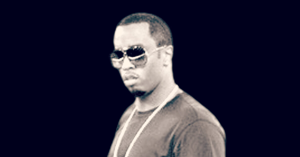 Portrait of a man wearing sunglasses and a black shirt, posing confidently against a dark background.