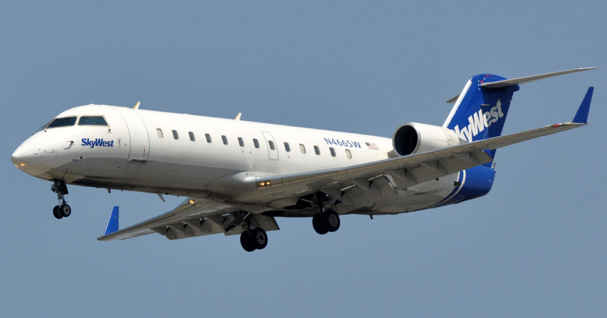 SkyWest Airlines regional jet approaching for landing against a clear blue sky.