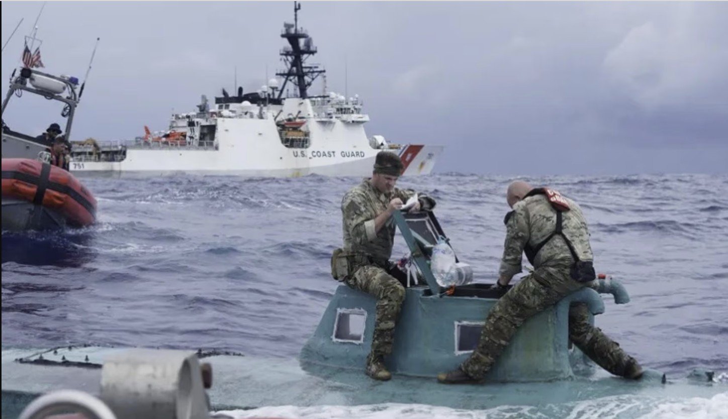 U.S. Coast Guard personnel inspect a small vessel at sea, with a larger Coast Guard ship in the background, showcasing maritime operations and rescue efforts.