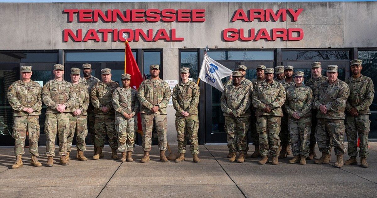 Group of Tennessee National Army Guard soldiers posing in front of their headquarters building, showcasing military camaraderie and service commitment.