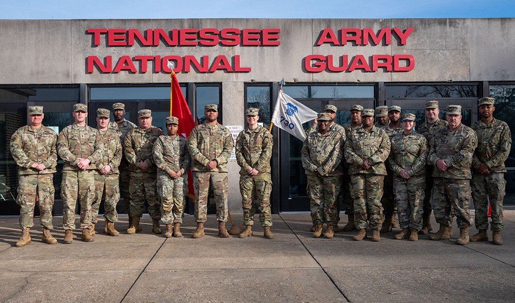 Group of Tennessee National Army Guard soldiers posing in front of their headquarters building, showcasing military camaraderie and service commitment.