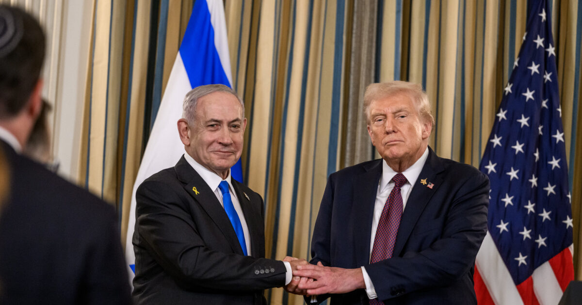 Israeli Prime Minister Benjamin Netanyahu and former U.S. President Donald Trump shake hands during a formal event, with flags of both nations in the background.