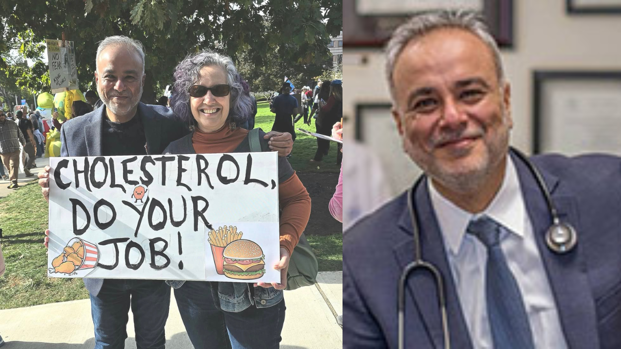 Two people hold a sign reading "Cholesterol, Do Your Job!" at a health awareness event, emphasizing the importance of managing cholesterol levels.