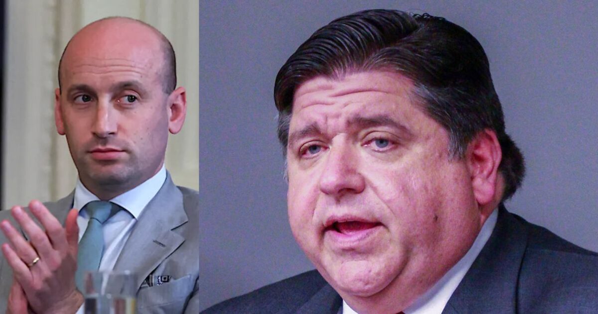 Two men engaged in discussion, one in a suit with a light blue tie and the other in a dark suit, both displaying focused expressions.