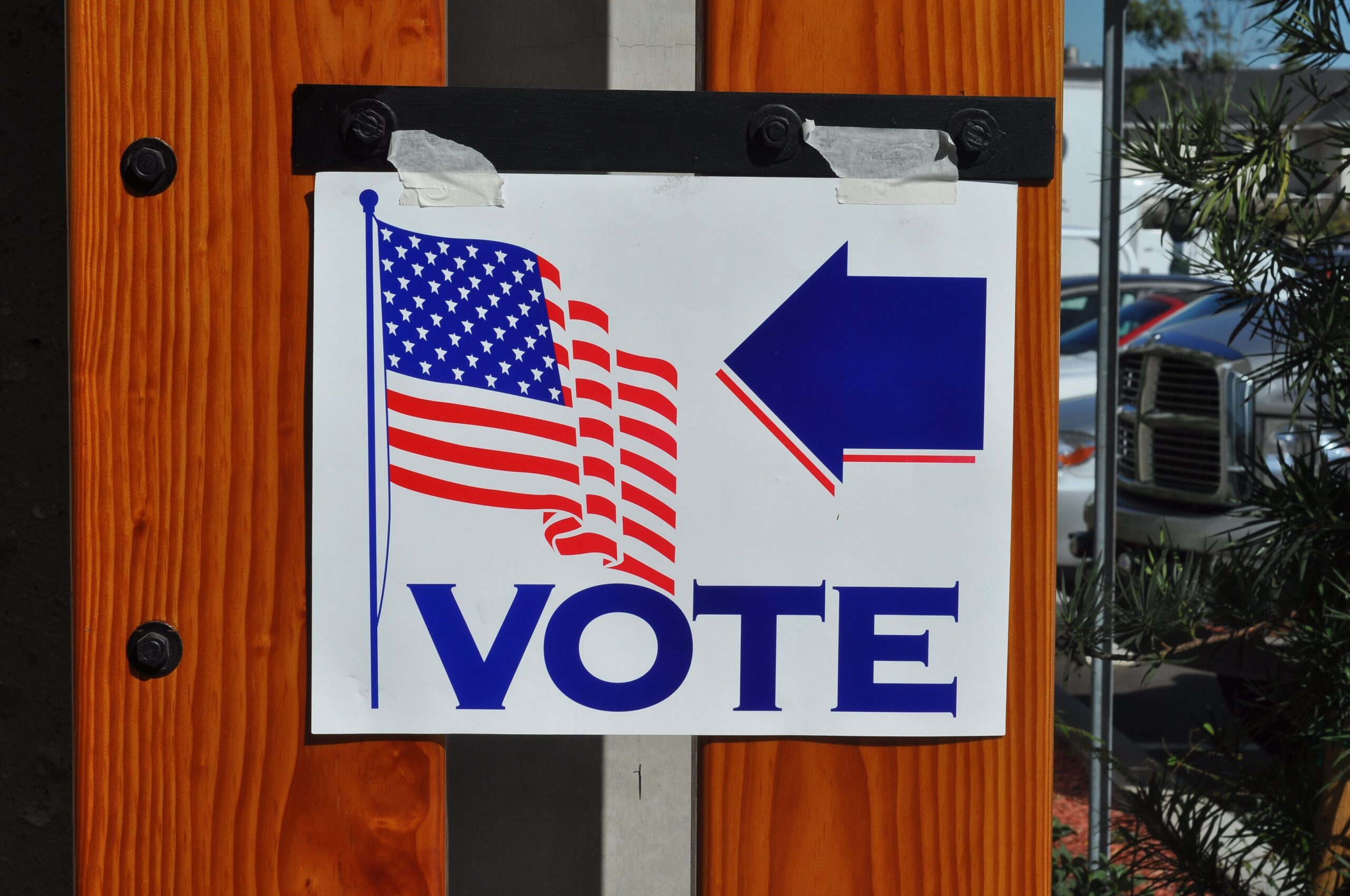 Voting sign with American flag and arrow directing voters to polling location.