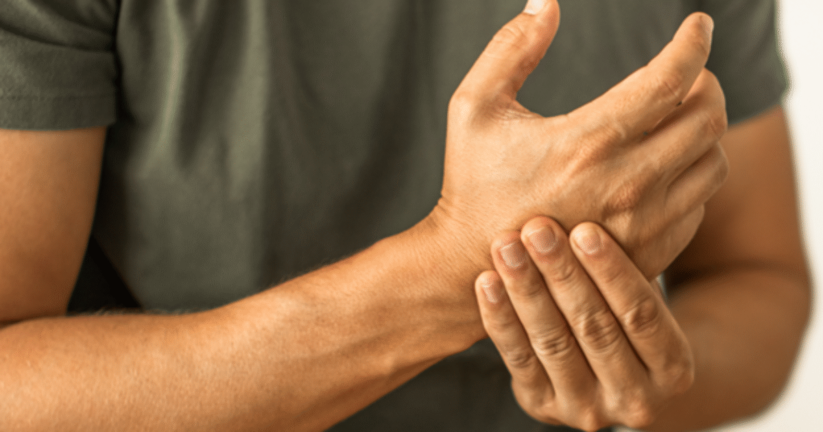 Person experiencing wrist pain while holding their wrist with one hand, indicating discomfort or injury.