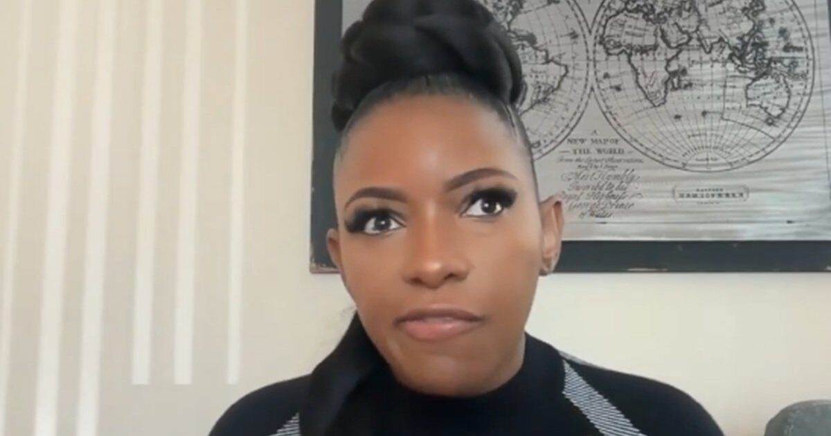 Woman with a stylish updo hairstyle speaking intently against a backdrop of world maps, showcasing a modern and engaged conversation setting.