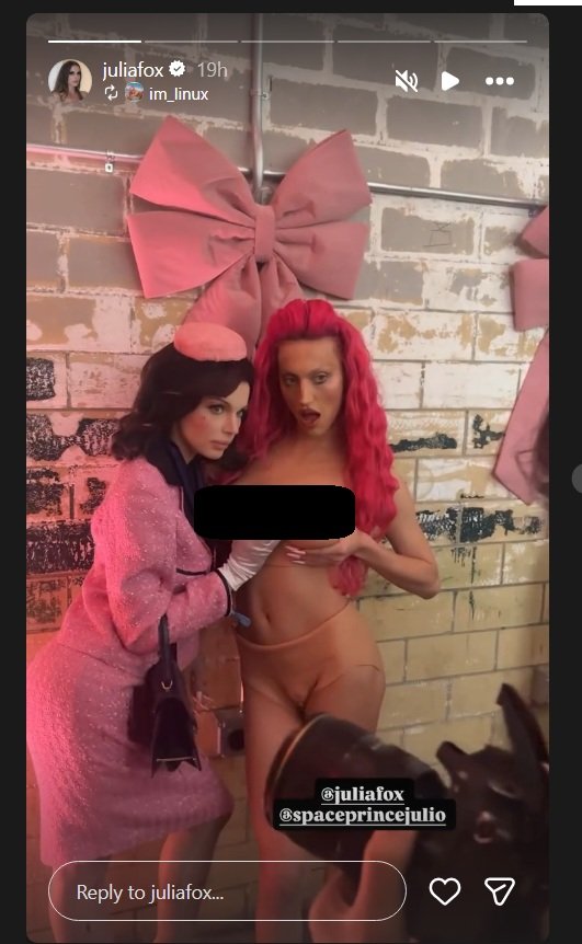 Two models pose together in a playful setting with pink bows, showcasing bold fashion and vibrant hairstyles.