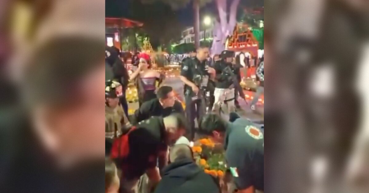 Crowd gathers around a colorful altar during a cultural festival, with participants engaged in traditional activities and police presence visible in the background.
