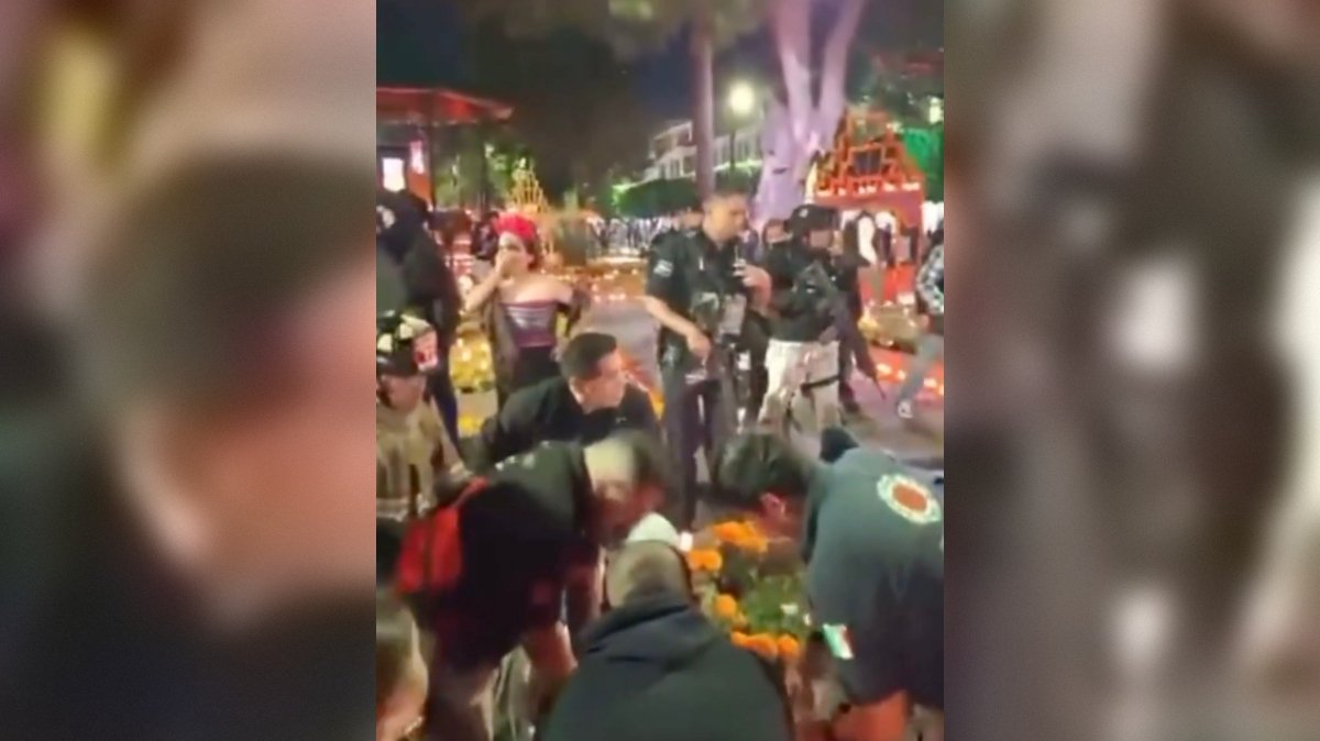 Crowd gathers around a colorful altar during a cultural festival, with participants engaged in traditional activities and police presence visible in the background.