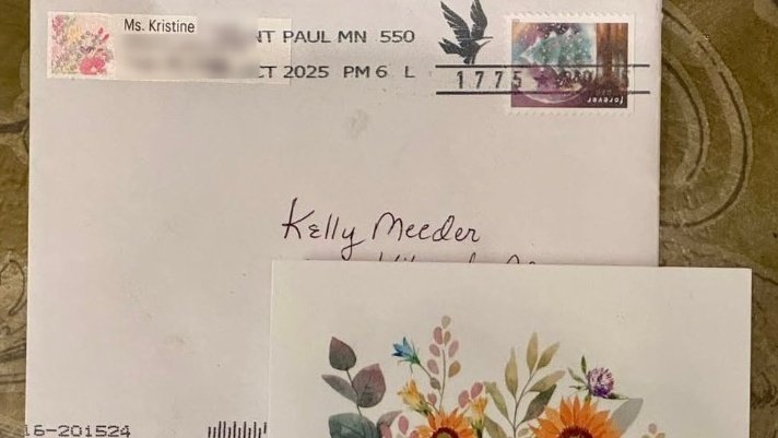 Envelope addressed to Kelly Meeder with floral card, featuring a postage stamp and handwritten details, showcasing personal correspondence.