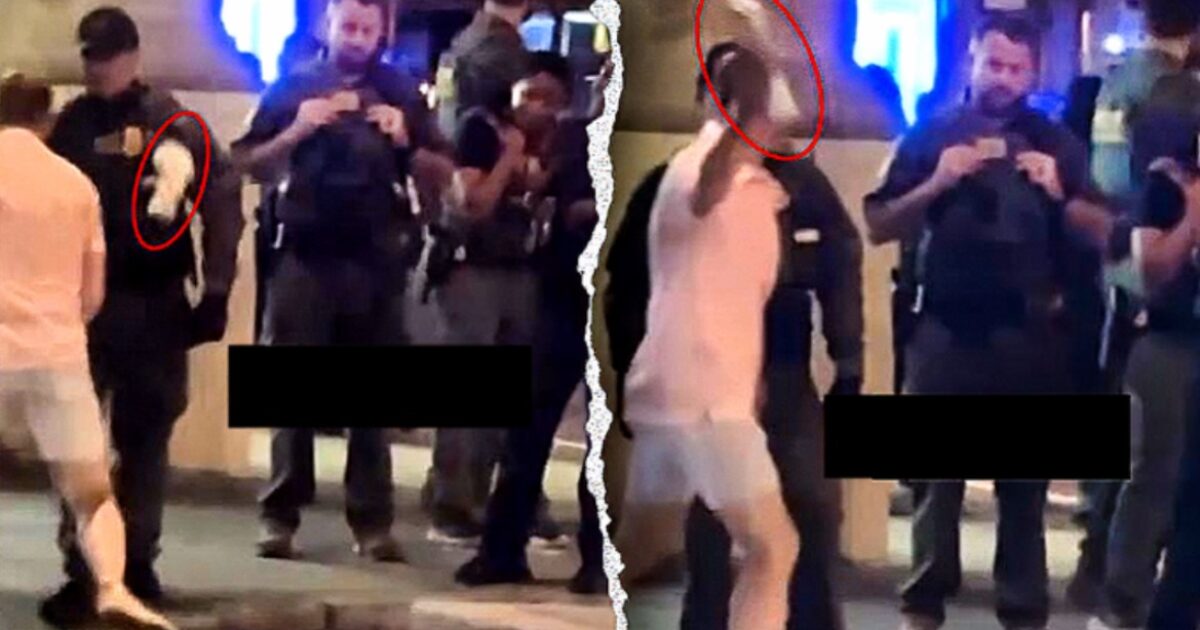 Police officers interact with a person in casual clothing during a nighttime street scene, capturing the moment on their phones.