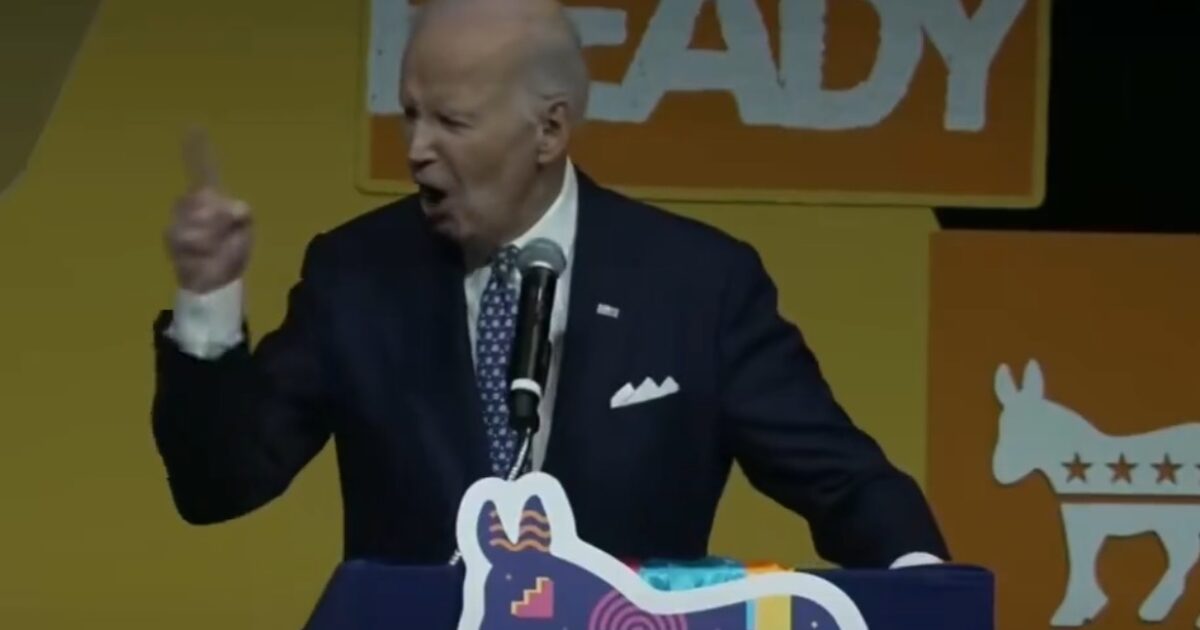 Joe Biden passionately speaks at a podium during a political event, emphasizing key points with animated gestures against a vibrant backdrop.