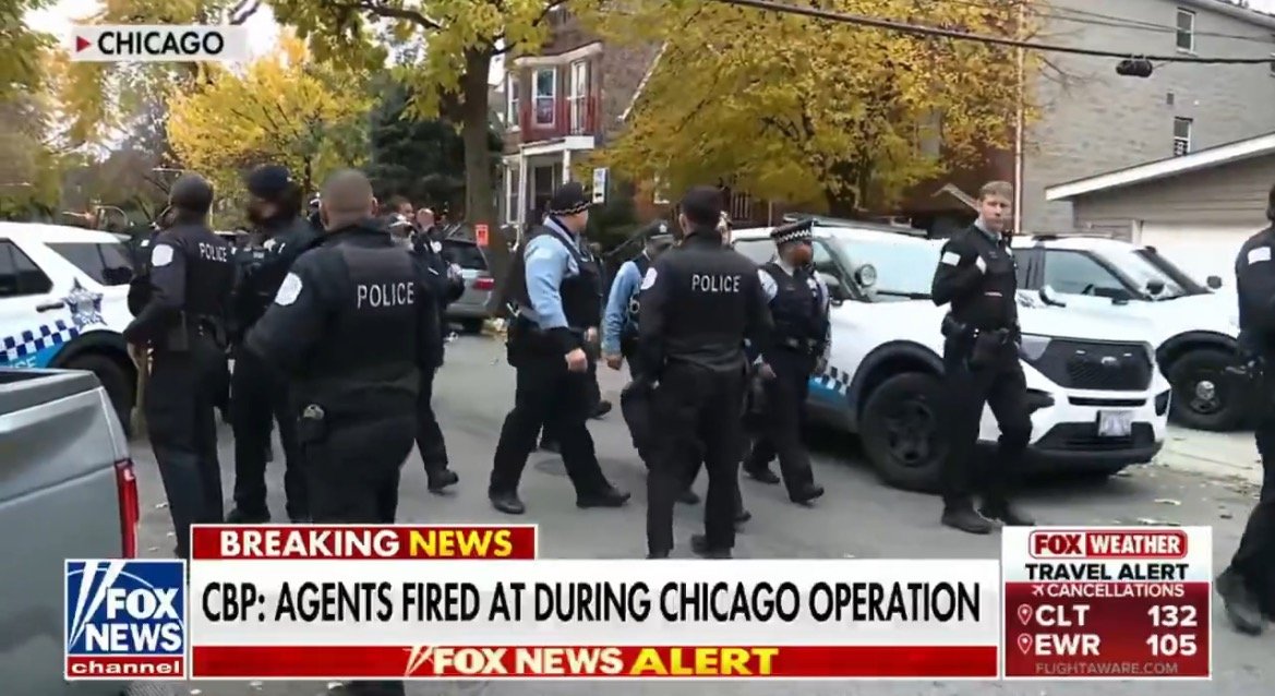 Police officers and agents are gathered at a scene in Chicago during a law enforcement operation with vehicles and autumn foliage in the background.