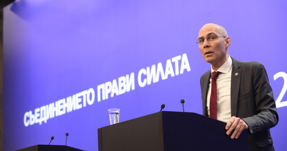 Speaker at a podium addressing an audience, with a backdrop featuring the phrase "Съединението прави силата," emphasizing unity and strength in a conference setting.