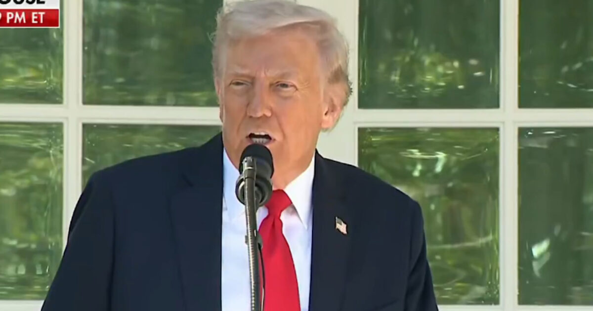 Donald Trump delivering a speech at the White House, addressing an audience with a microphone in front of large windows.