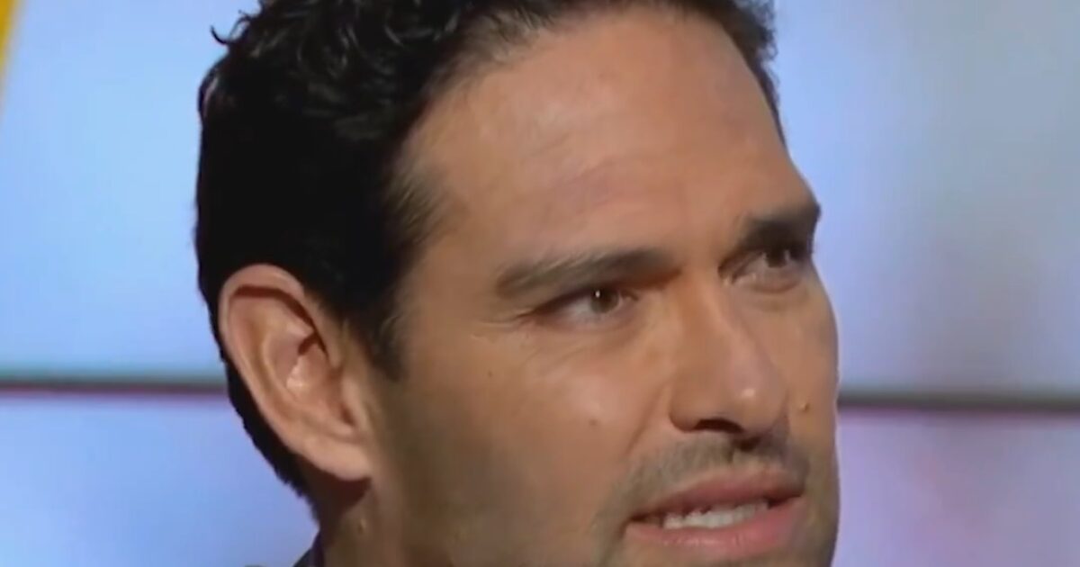 Close-up of a man with dark curly hair and a serious expression, discussing sports analysis on a television program.