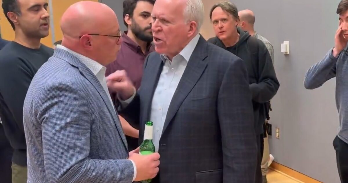 A heated discussion takes place between two men in a casual setting, while others observe in the background.