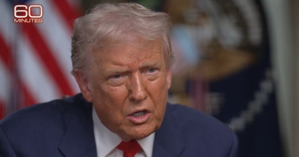 Close-up of a man speaking passionately during a televised interview, with American flags in the background, highlighting a significant moment in political discourse.