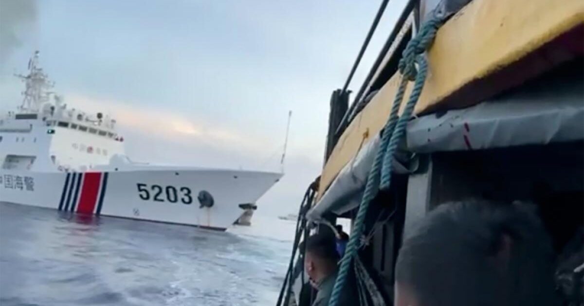 A close-up view of a fishing vessel alongside a large coast guard ship marked with the number 5203, set against a cloudy sky.