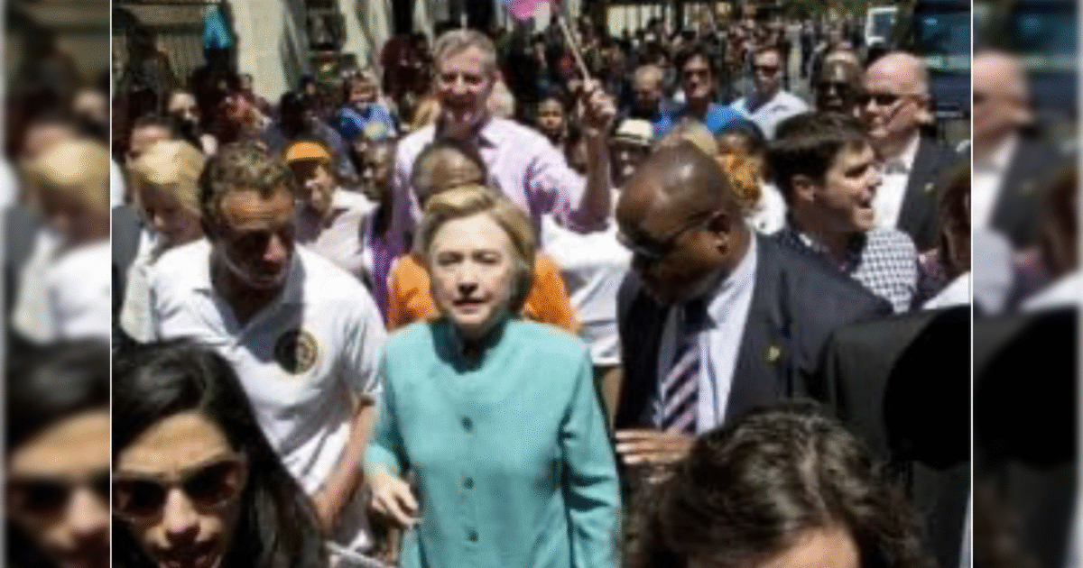 Hillary Clinton walks through a crowd at a public event, surrounded by supporters and officials, showcasing civic engagement and community involvement.