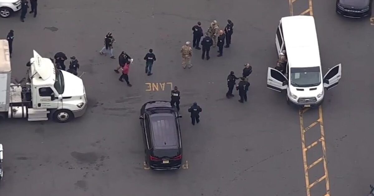Law enforcement personnel gather at a scene with multiple vehicles, including a truck and a van, indicating an ongoing investigation or operation.