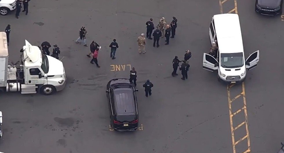 Law enforcement personnel gather at a scene with multiple vehicles, including a truck and a van, indicating an ongoing investigation or operation.