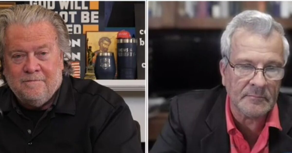 Two men engaged in a discussion, one seated at a desk with a microphone and the other in front of a computer, against a backdrop of books and framed images.