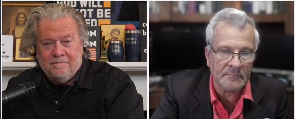 Two men engaged in a discussion, one seated at a desk with a microphone and the other in front of a computer, against a backdrop of books and framed images.