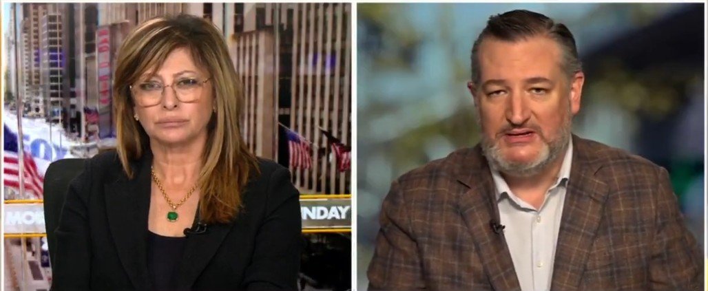 Television interview featuring a female host and a male guest discussing current events, with a cityscape background visible through a window.