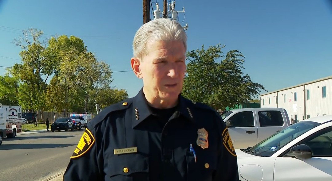 San Antonio police chief addressing the media at a scene with emergency vehicles in the background, highlighting public safety efforts.