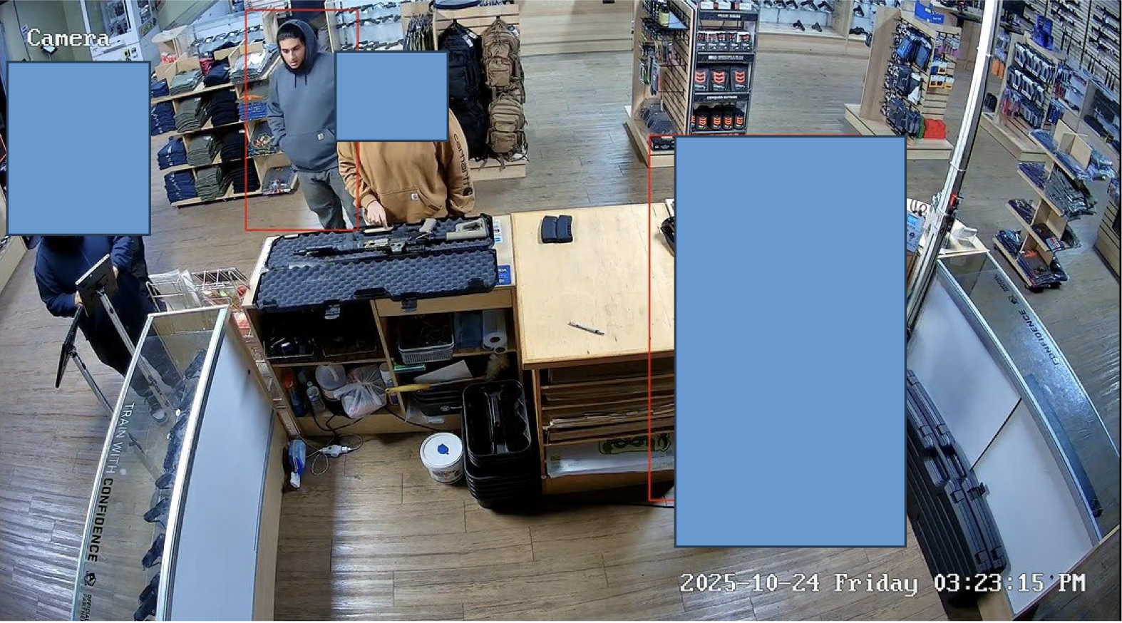 Surveillance image inside a retail store showing customers interacting near a display of firearms and gear, with timestamp and camera label visible.