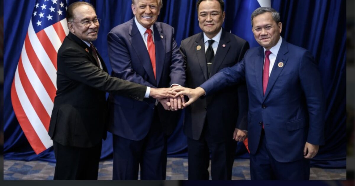 Leaders from different nations pose together, united in a handshake, with the American flag displayed prominently in the background.