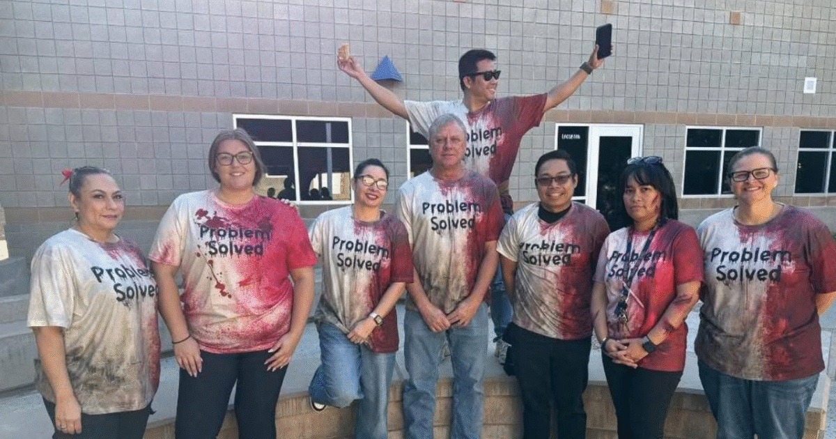 Group of eight individuals wearing matching "Problem Solved" t-shirts with a red and white design, posing outdoors in front of a building.