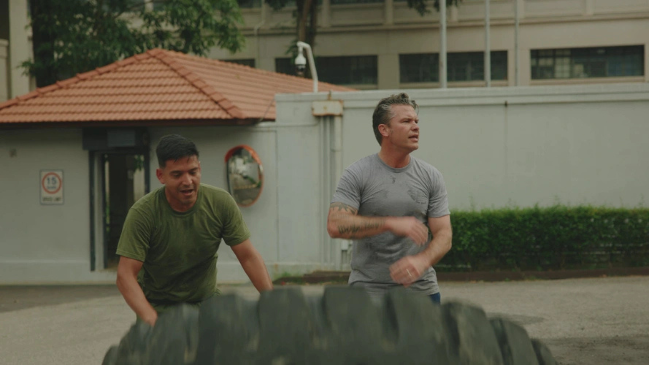 Two men engaging in a tire flipping workout outdoors, showcasing strength training and teamwork in a fitness setting.