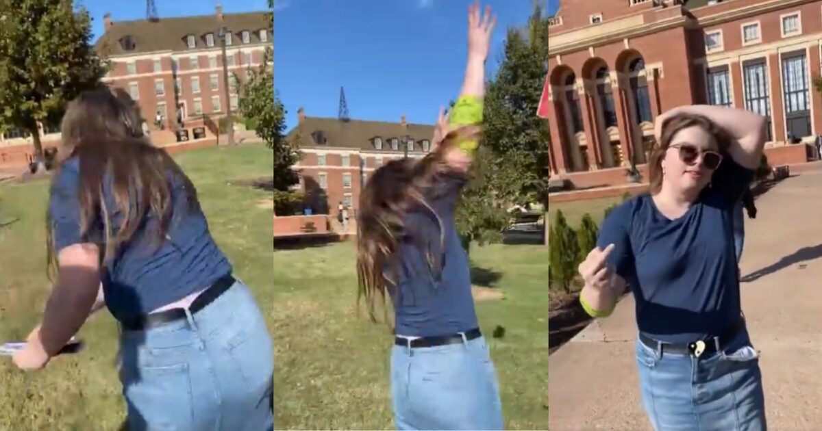 Young woman in casual attire enjoying a sunny day outdoors, playfully posing in front of a college building while showcasing a carefree attitude.