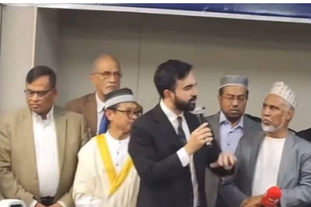 Group of men at a conference, with one speaker holding a microphone and engaging the audience, showcasing cultural diversity and community involvement.