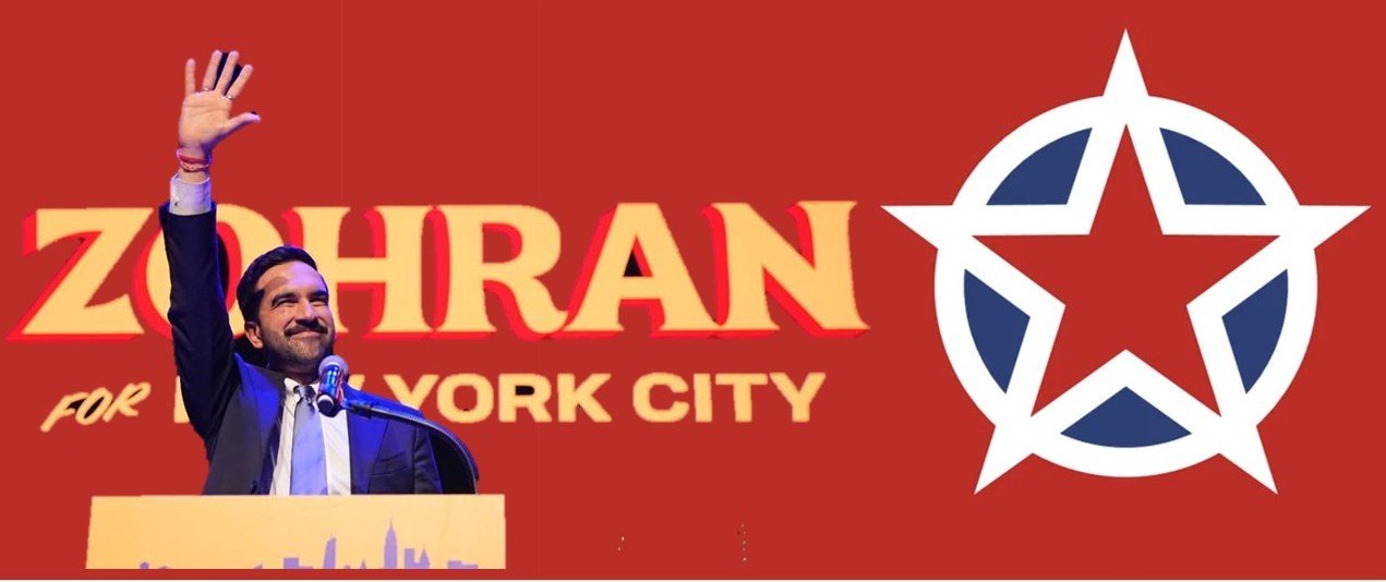 A smiling politician raises his hand at a campaign event for Zohran Mamdani in New York City, with a prominent logo in the background.